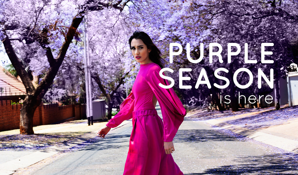 
          Jacaranda season in Pretoria - a model walking across a purple jacaranda strewn street.
        